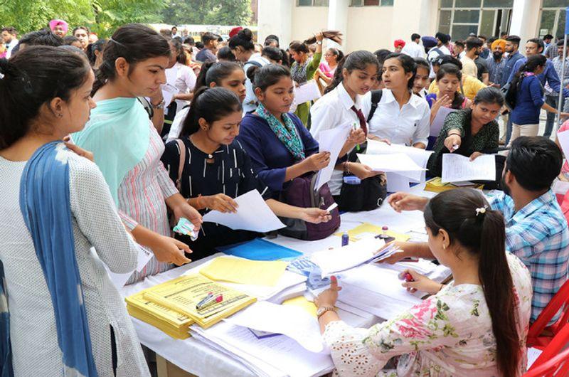 Busy outdoor registration desk with applicants submitting documents at high volume